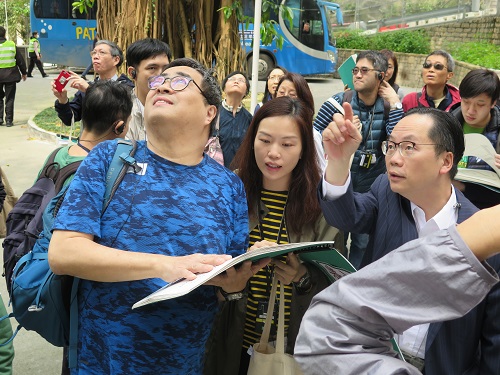 Two volunteers (right one and right two) assiting a visually imapired (left one) to read the guide book and describing the attraction 